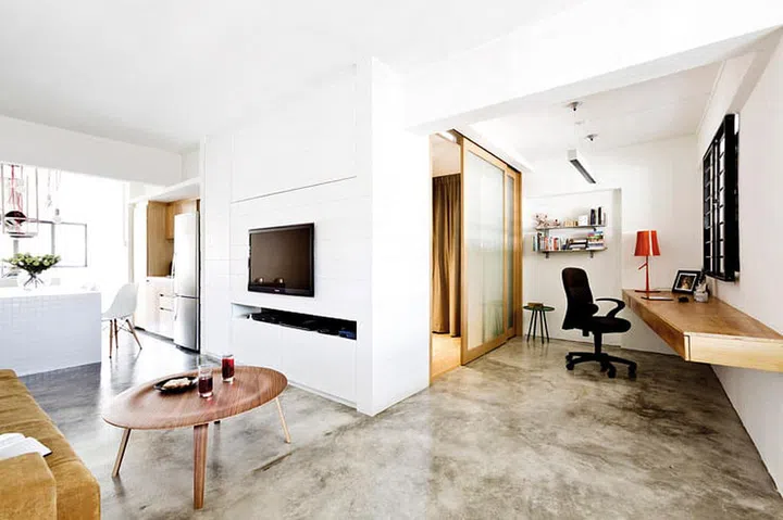 The uneven-toned cement screed floor gives and edgy feel to the minimalist space. Coffee table, side table, red lamp and clear glass vase from Xtra.