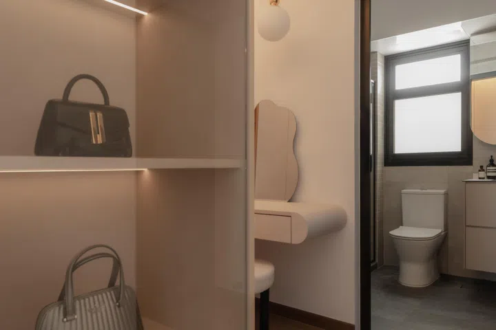 Glass-fronted display shelves lead into the vanity nook and bathroom beyond, creating a seamless transition between dressing, grooming, and daily routines.