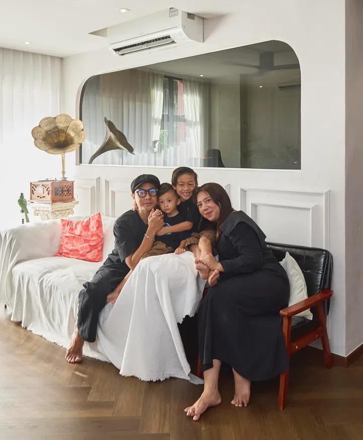 The homeowners with their two children in the living area, where wainscoting and arched openings introduce the home’s layered mix of classical detail and everyday family life.