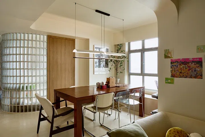 The dining area sits flanked by the curved glass dome and sea-facing windows, where soft corners and clear sightlines allow light to travel across the open plan.