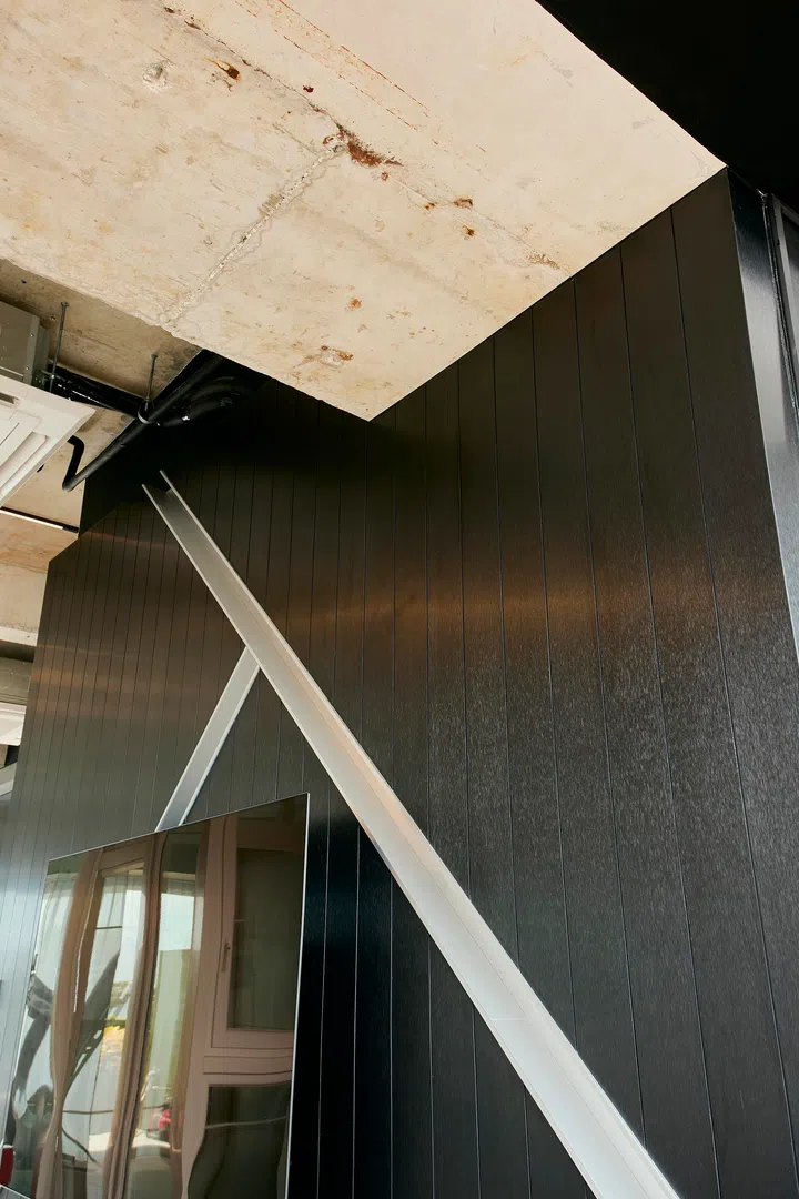 A dark feature wall with vertical detailing and a diagonal metal element introduces a stronger, more graphic expression to the space.