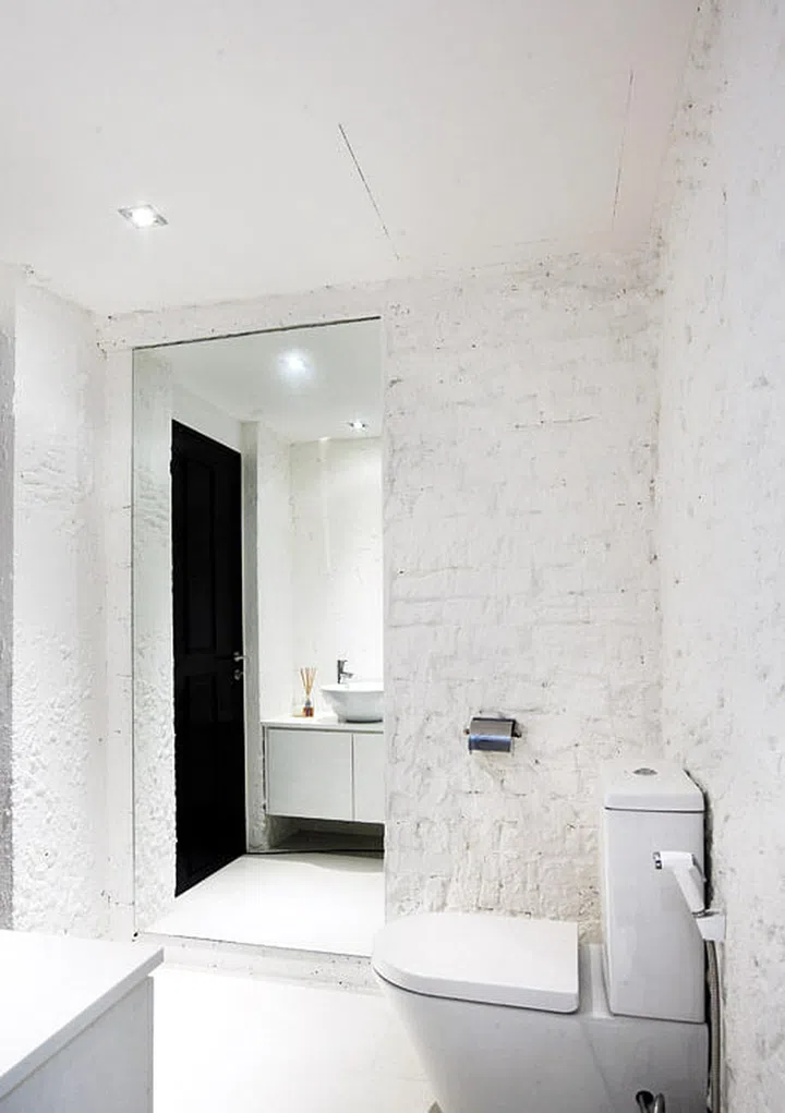 The interior designer applied the same exposed-brick treatment to the powder room to play against the smooth white finish of the ceramics.