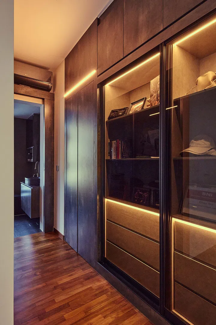 Dark-toned storage cabinet leading into the master bathroom, contributing to the room’s sultry and sophisticated ambience.