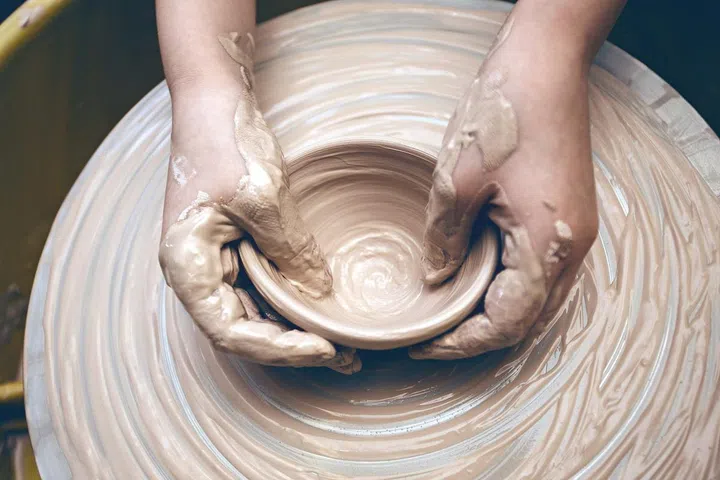 ceramic workshop - the girl makes a pot of clay on a potter's wheel. hands closeup