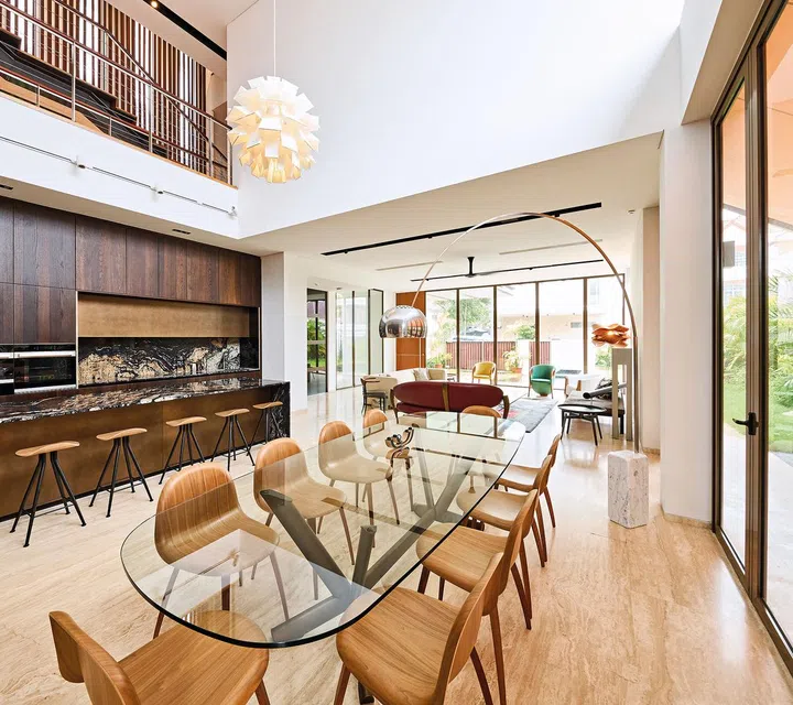 An Arco floor lamp arches gracefully over the Cattelan Italia Planer dining table and Gubi 3D dining chairs.