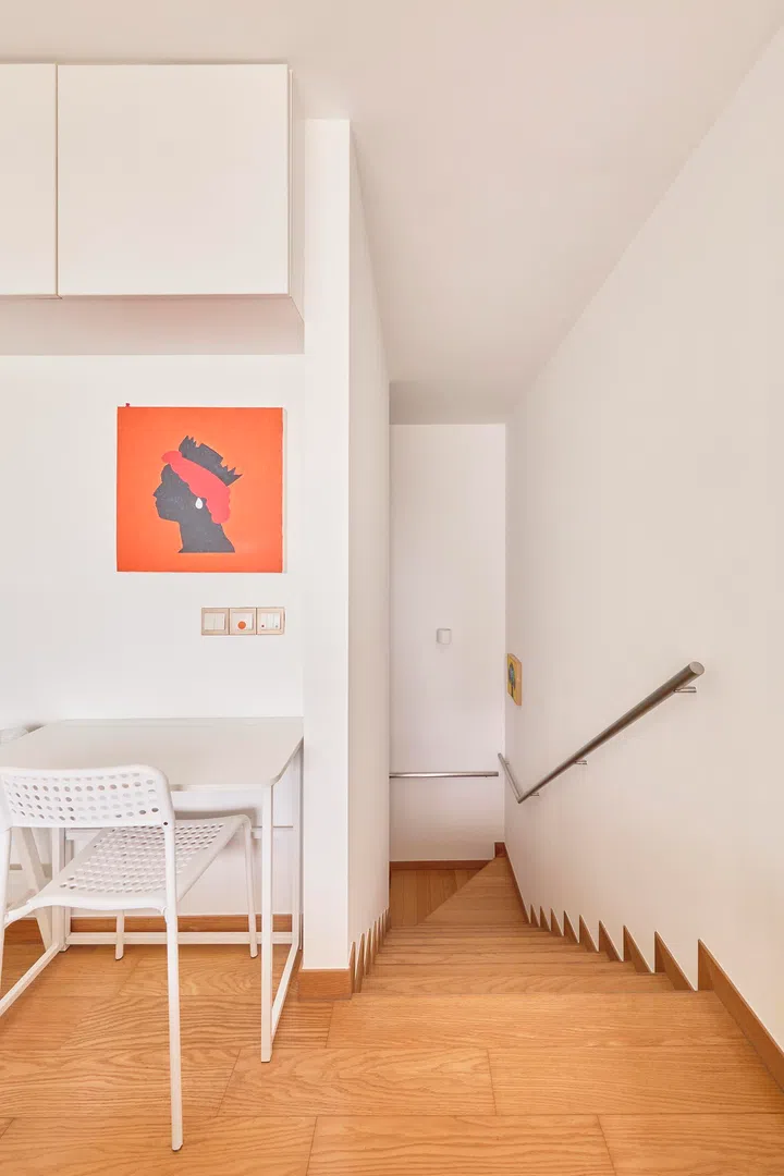 A small desk sits at the stair landing, marking the transition between the private upper level and the living space below.
