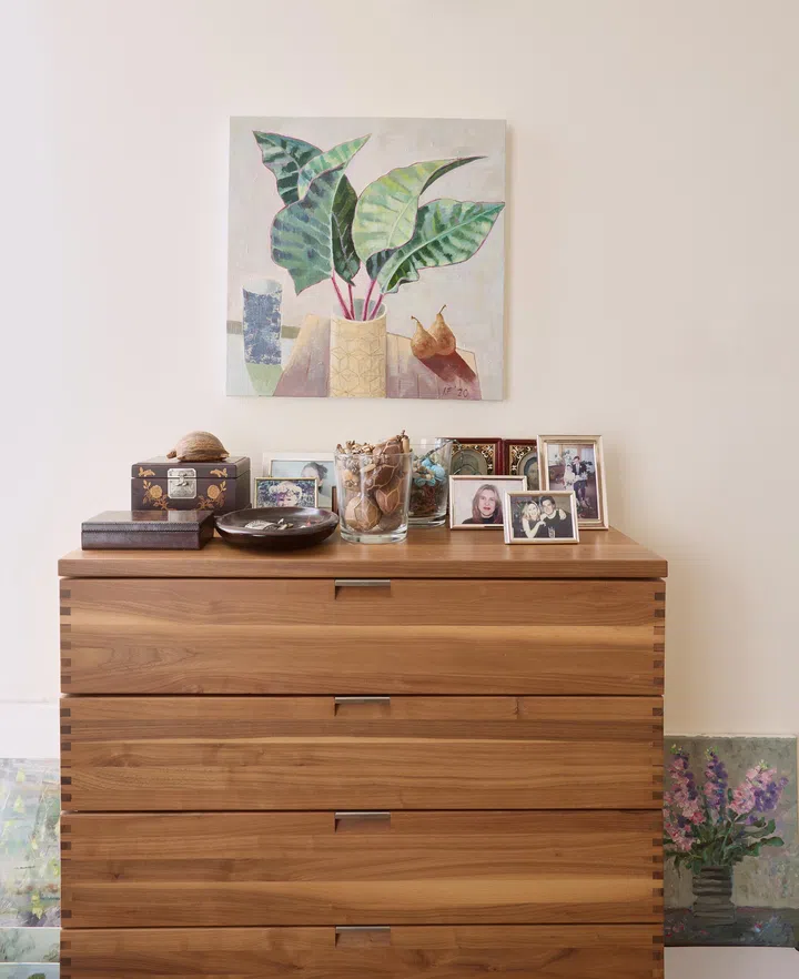 A wooden dresser topped with framed photos and cherished keepsakes in a softly lit room.