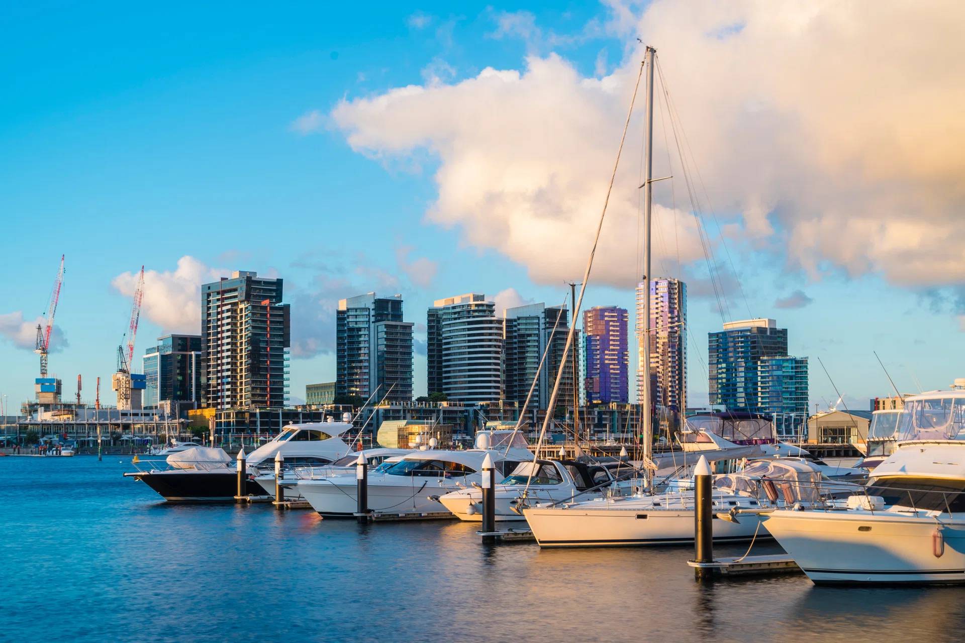 View of yachts in marina and modern residential buildings in Docklands, Melbourne at sunset.