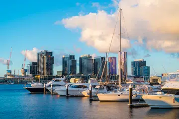 View of yachts in marina and modern residential buildings in Docklands, Melbourne at sunset.