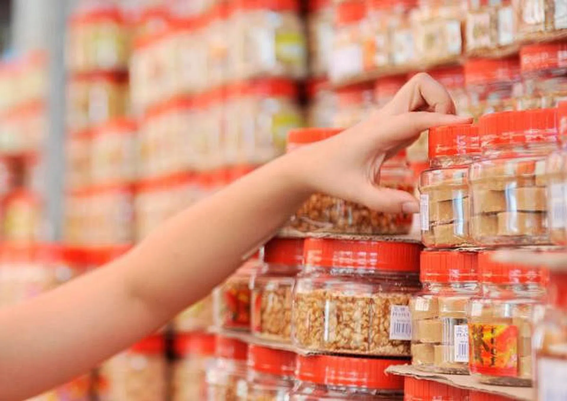 Hand picking up a jar of Chinese New Year biscuit goodies cookies. Photo by The Straits Times