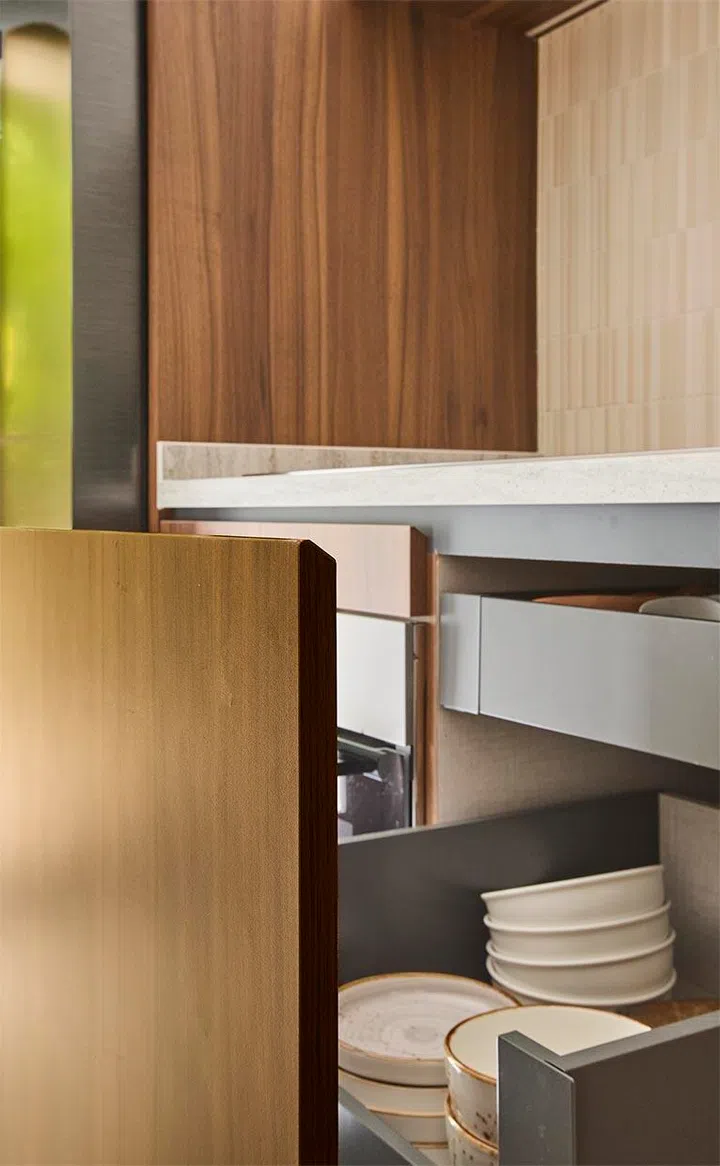 Integrated drawers and compartments keep everyday items within easy reach, maintaining the kitchen’s clean, continuous lines.
