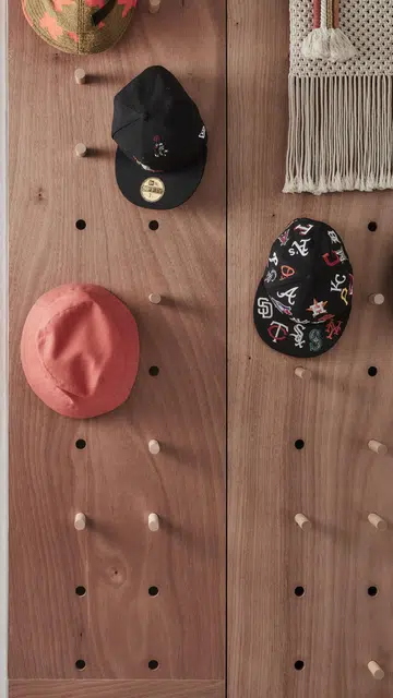 A wooden peghole wall organisation rack holds caps and hats neatly in this 1,367 sq ft 5-room HDB at Bedok Reservoir Road. 