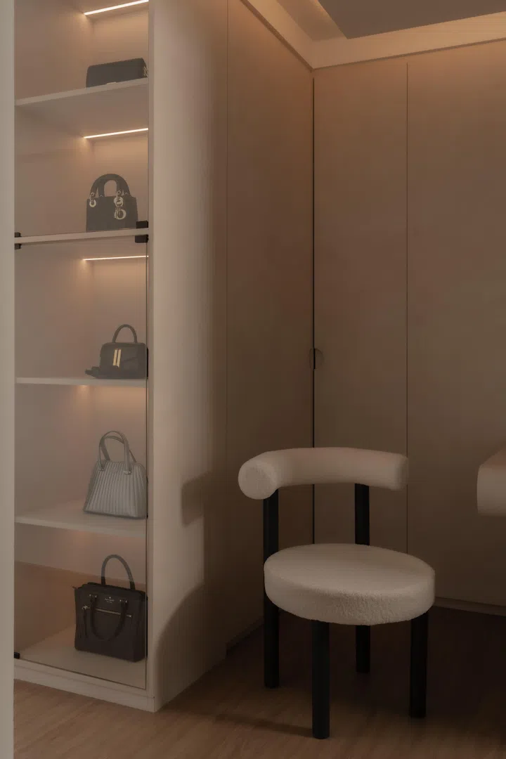 Glass-fronted display shelving and a curved vanity counter transform the wardrobe into a personal dressing space, balancing visibility with concealment.