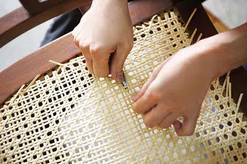 Rattan Furniture Craftsman at work weaving a chair