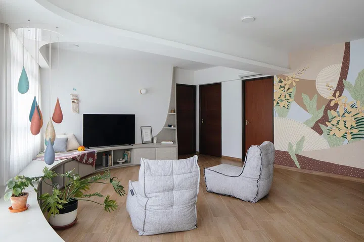 The curve beside the television tapers off into a little display shelf, while the rest of the space is made whimsical and playful with the use of bright colours and wallpaper.