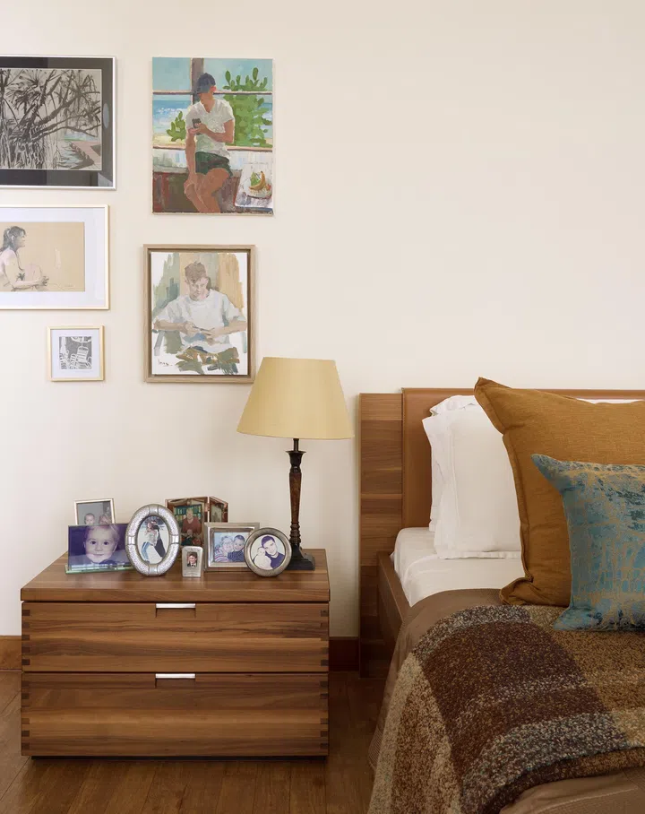 A warmly decorated master bedroom with wood furniture and personal portraits on the walls.