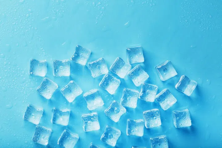 Ice cubes with water drops scattered on a blue background, top view. Refreshing ice. Photo 123RF
