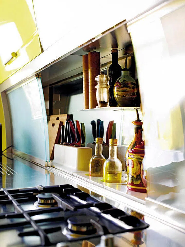 The best place to store your condiments and cooking utensils isn't next to your stove, but just behind it. But to keep them free from grease, make use of a sliding glass panel that doubles as your backsplash.