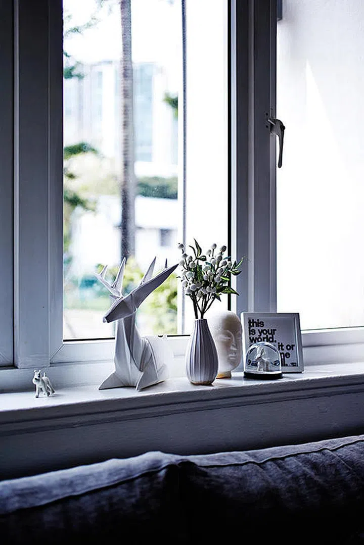 In one corner, an eclectic collection of objects graces a windowsill, including a whimsical origami-inspired sculpture and delicate vases.