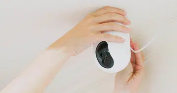 woman is installing surveillance cameras on ceiling at home