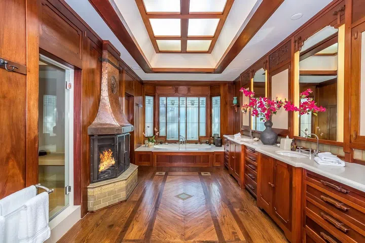 The wood-paneled primary bathroom features a copper-hooded fireplace.