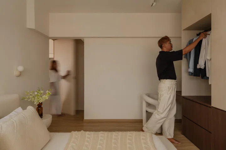 In the master bedroom, a long wardrobe wall conceals storage, with an open hanging zone designed for jackets worn once.