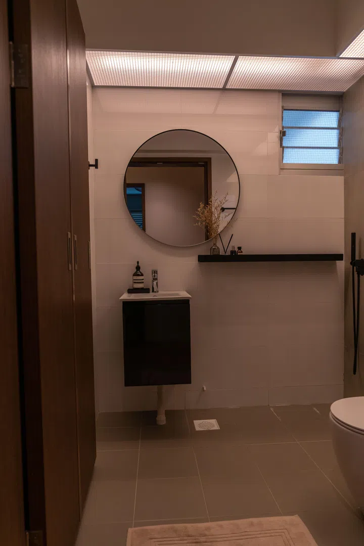 The bathroom is clad in large-format matte tiles, with slim black fittings adding contrast to the otherwise neutral palette.