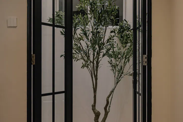 The former air column on the second floor has been transformed into a framed garden view with french doors and a faux Olive plant.