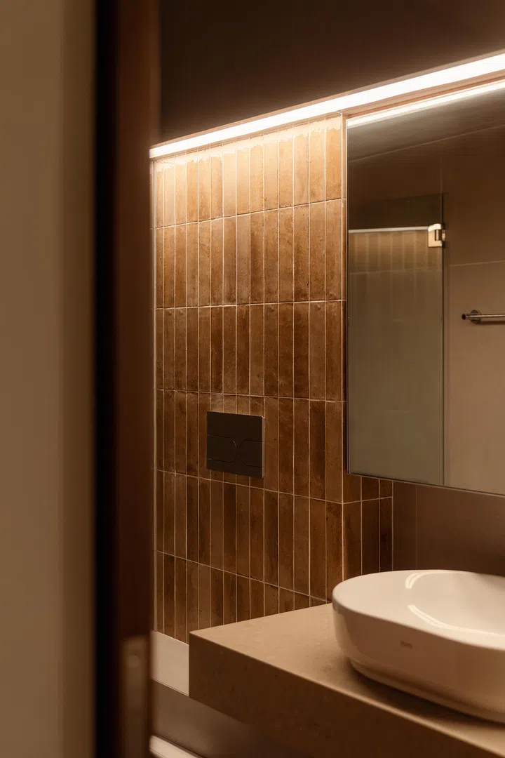 Vertical brown tiles introduce warmth and texture, balanced by simple fittings.