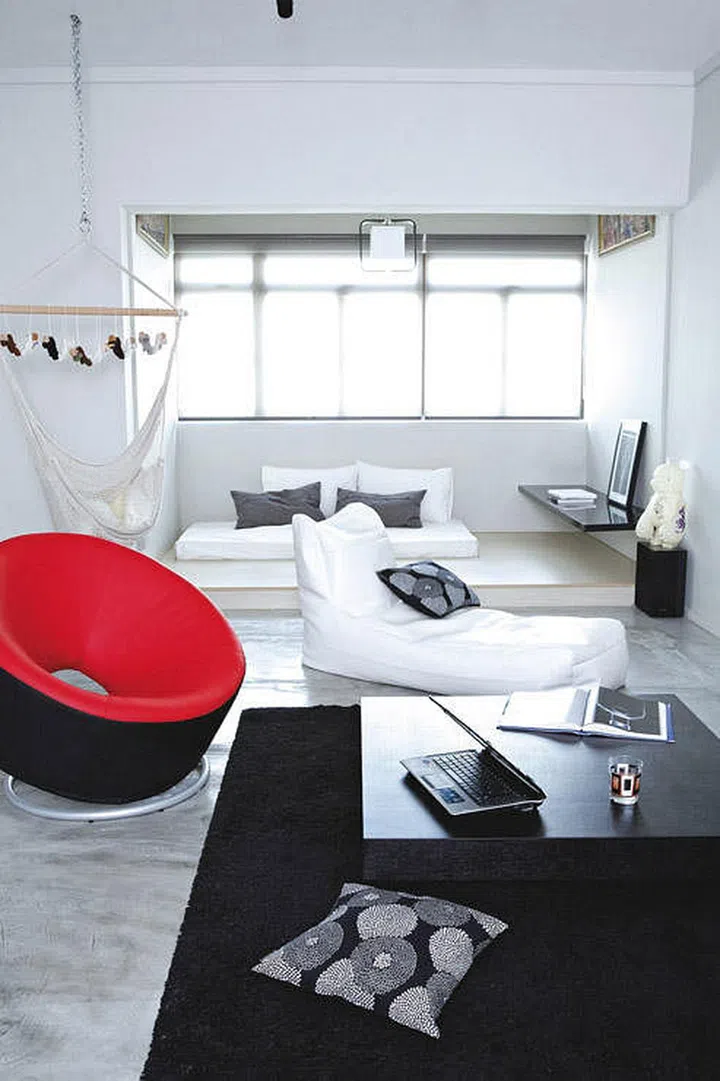 The red-and-black doughnut chair, with its geometric shape and sharp colour, is a visual point of interest amid the living area’s white and black furnishings.