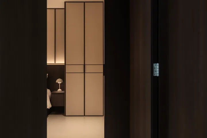 The master bedroom door is similarly concealed within the wall panelling, allowing the living spaces to maintain a clean, uninterrupted architectural language.