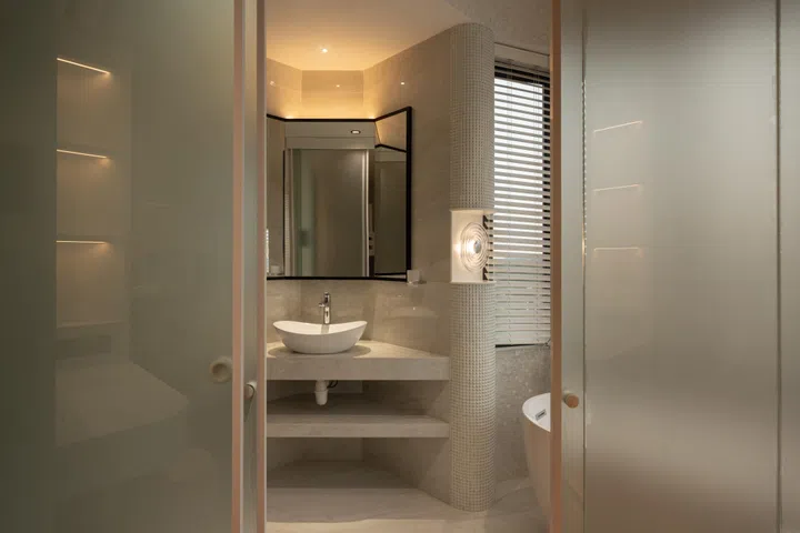 At first glance, the bathroom reads as a quiet extension off the main spine, its full shape only revealing itself as you move further in.