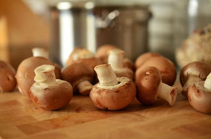 Close up of a bunch of mushrooms on a wooden chopping board.