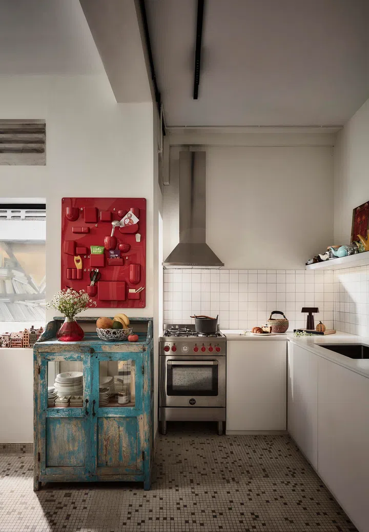 A rustic cabinet left behind by the previous owner was retained and repurposed, its weathered patina adding character while holding everyday kitchen items in open view.