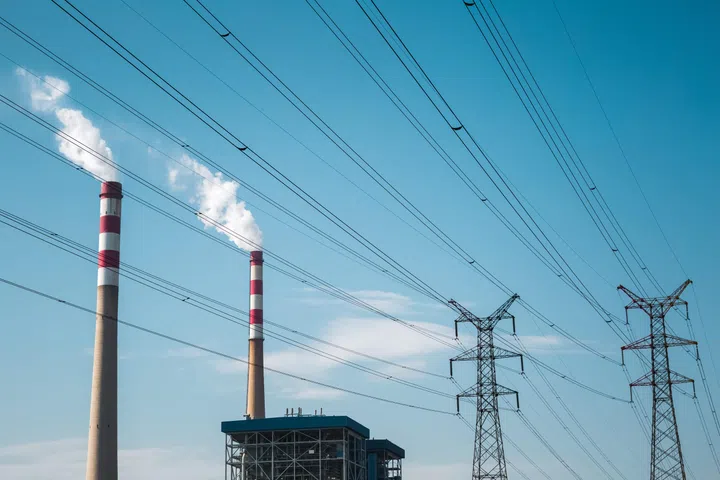power plant chimney and high voltage transmission pylon with blue sky