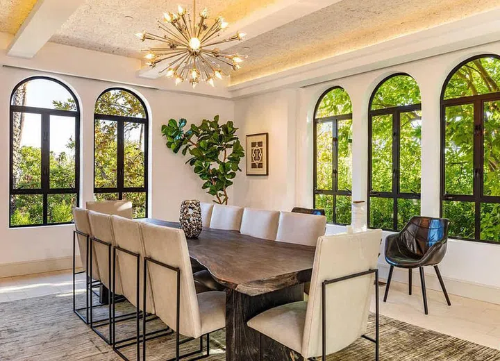 Rihanna's beautiful dining room is fitted with cathedral-like arched windows and a hanging pendant light. Image by Truila