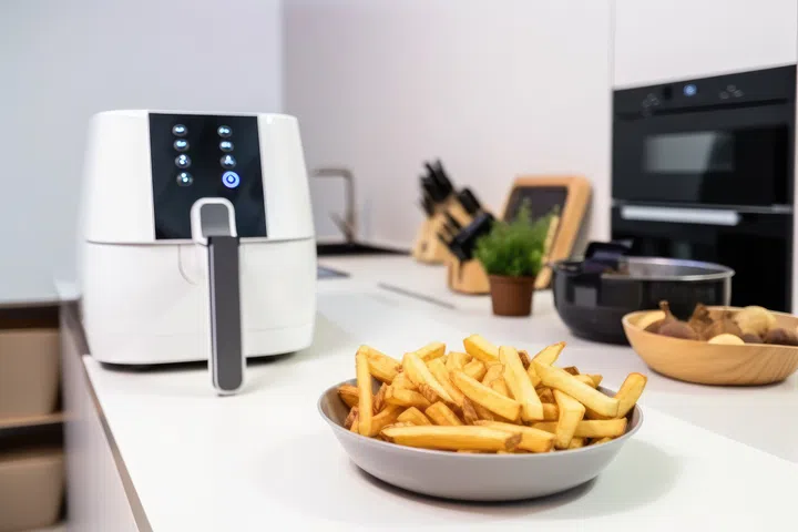 French fries in a bowl on a white table in a modern kitchen. Generative AI