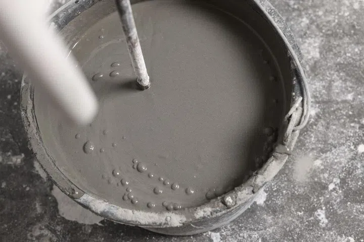 Mixing concrete in bucket indoors, closeup view. Image from 123RF