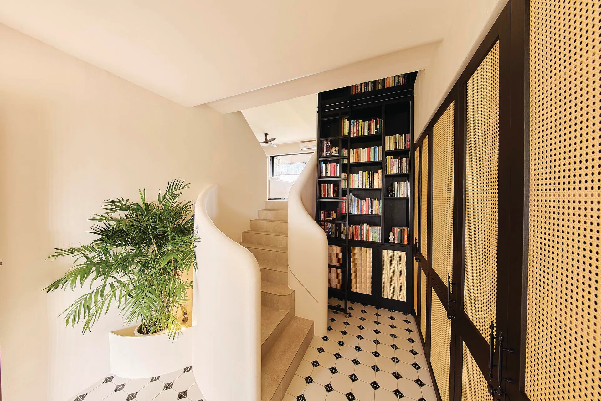 Minimalist stairwell juxtaposed against colonial-style rattan cabinets in a 3-bedroom condo (1,800 sq ft) in Pandan Valley, designed by Insight.Out Studio.