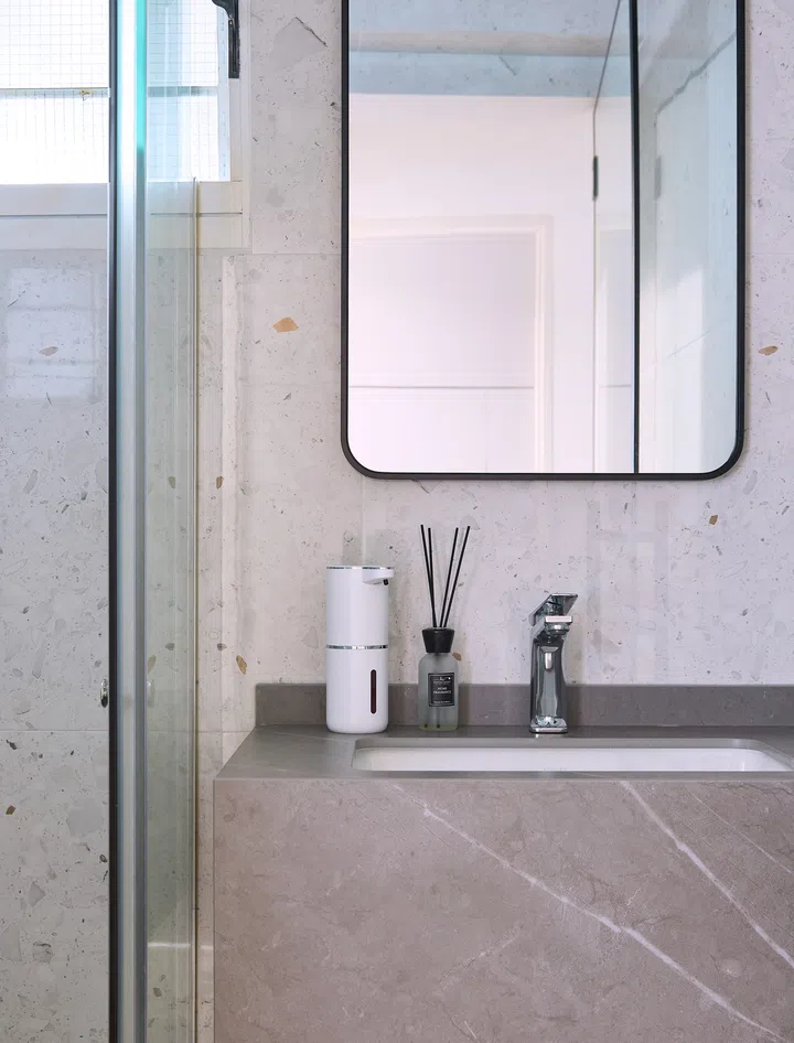 A minimalist bathroom with terrazzo wall tiles, designed in harmony with the home’s understated aesthetic.