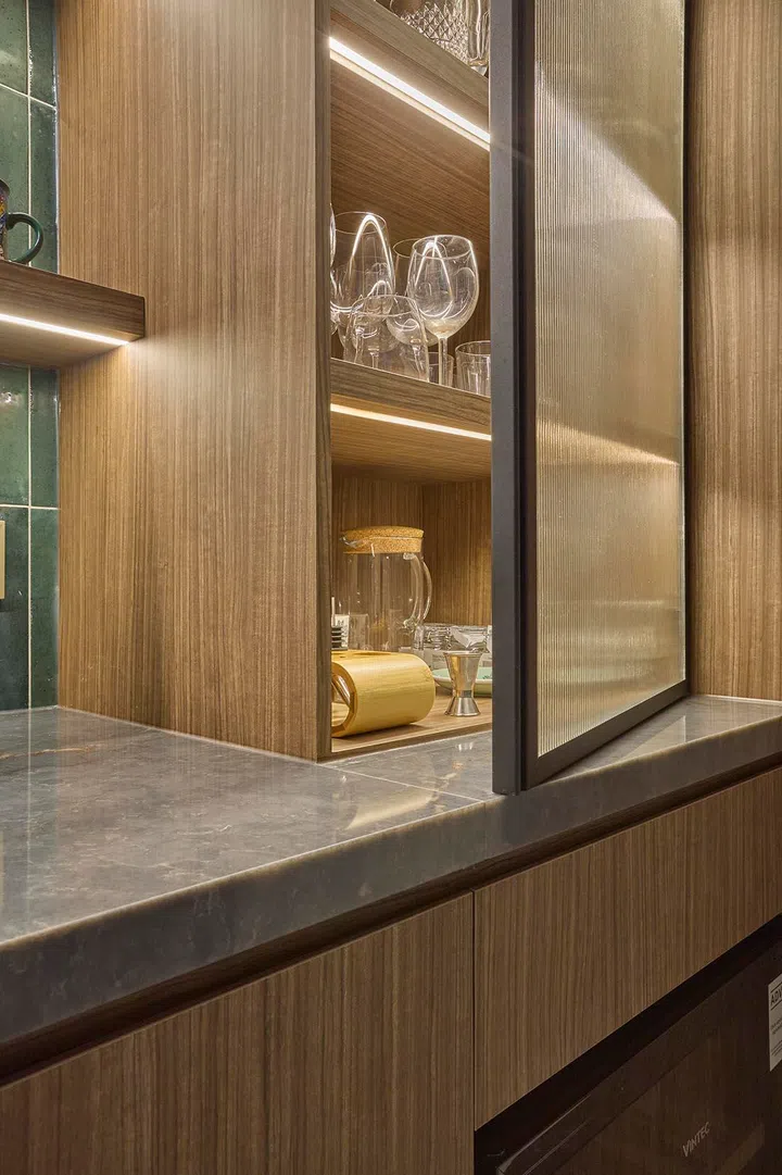 Fluted glass panels soften the display, partially concealing glassware while maintaining a sense of depth and texture.