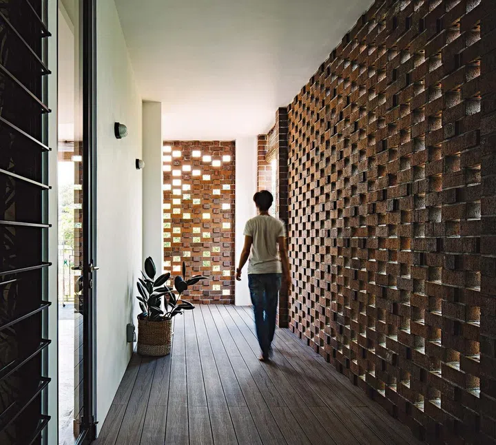 A man walking along a shaded verandah