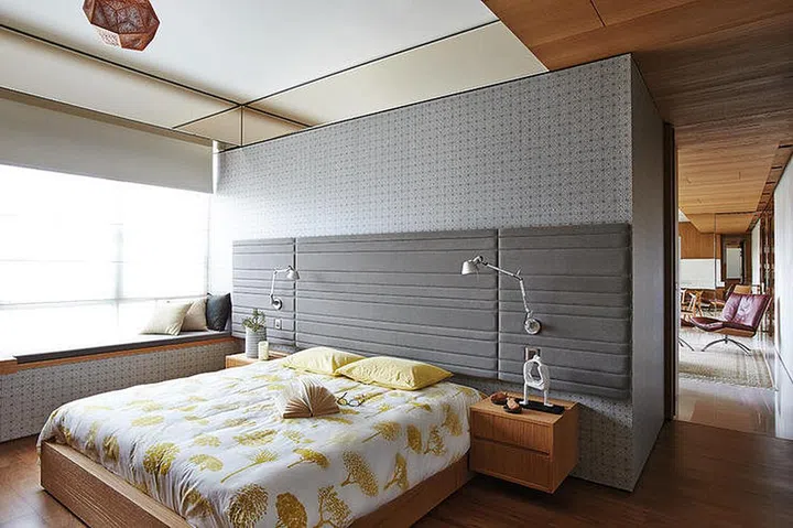 A plush headboard in the same hue as the patterned grey wallpaper creates a muted, soothing effect in the master bedroom in William Png's white and wood 3-bedroom condominium off Orchard Road.