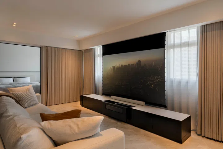 The living area is anchored by a projector-friendly wall and long sofa, designed for openness and flow.