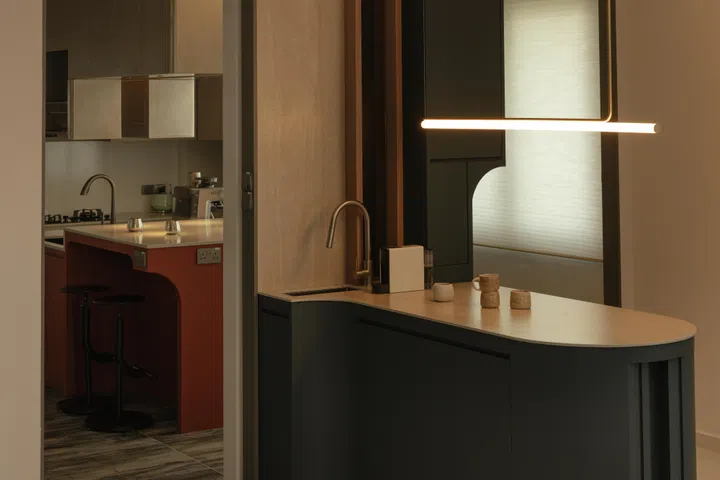 The blue-toned island marks the transition into the kitchen, introducing a softer, more informal counterpoint to the dining area.