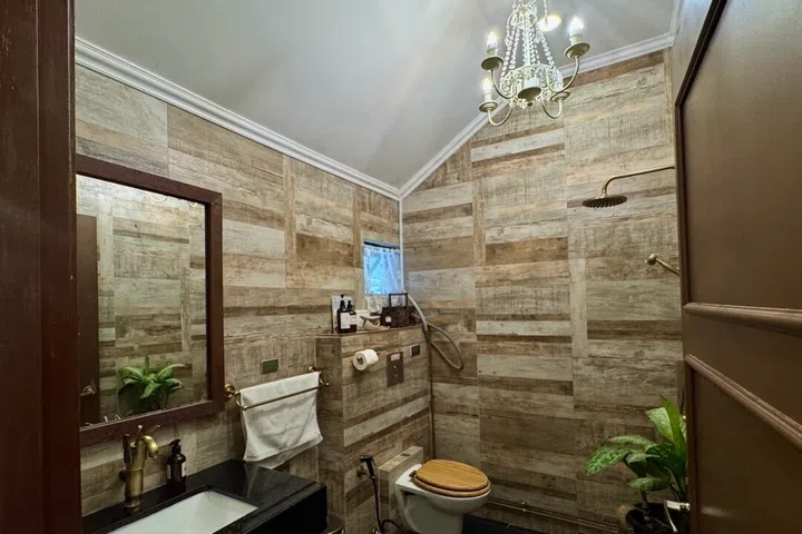 Elegant brass fixtures elevate the rustic bathroom, where a hose connection leading directly to the outdoor apiary invites guests to hear the subtle buzzing of bees as they freshen up.