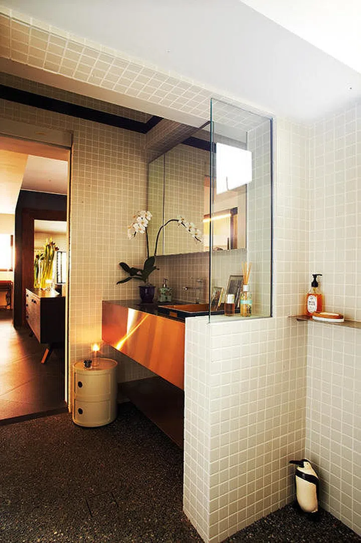 White mosaic tile bathroom walls with a stark brass sink countertop gives this bathroom a clean, neutral, yet modern boutique hotel bathroom design vibe.