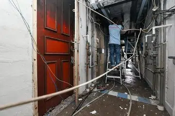 Electricians fixing the wires outside the 10th-floor unit at Block 4 Marsiling Road after the fire on 15 February 2024. PHOTO: LIANHE ZAOBAO