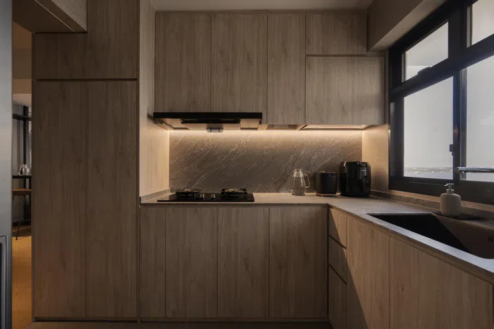 Light wood cabinetry and dark stone surfaces bring warmth and contrast to the compact kitchen.
