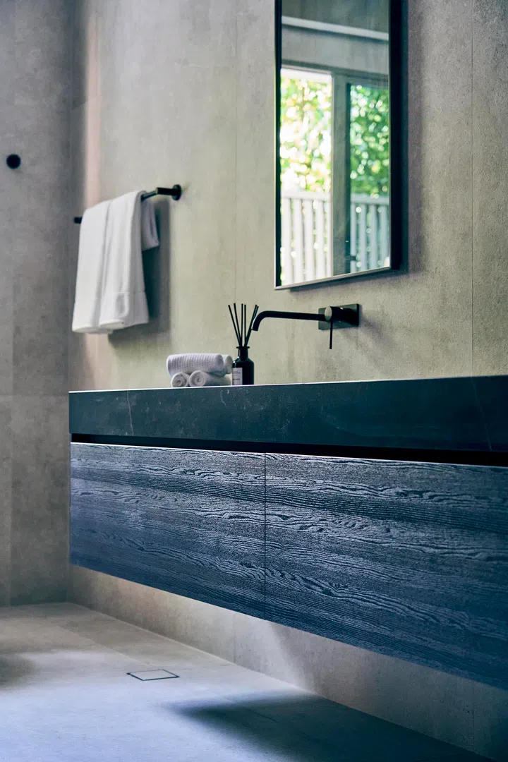  Textured timber cabinetry contrasts with sleek stone surfaces, balancing warmth and precision.
